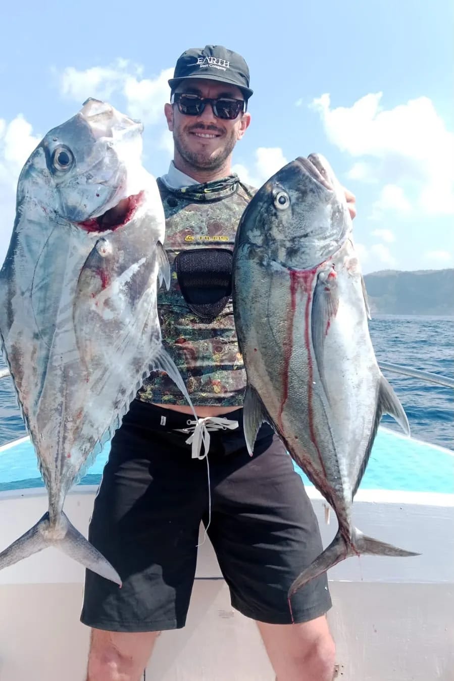 A guest on board holding two giant trevally caught on a charter