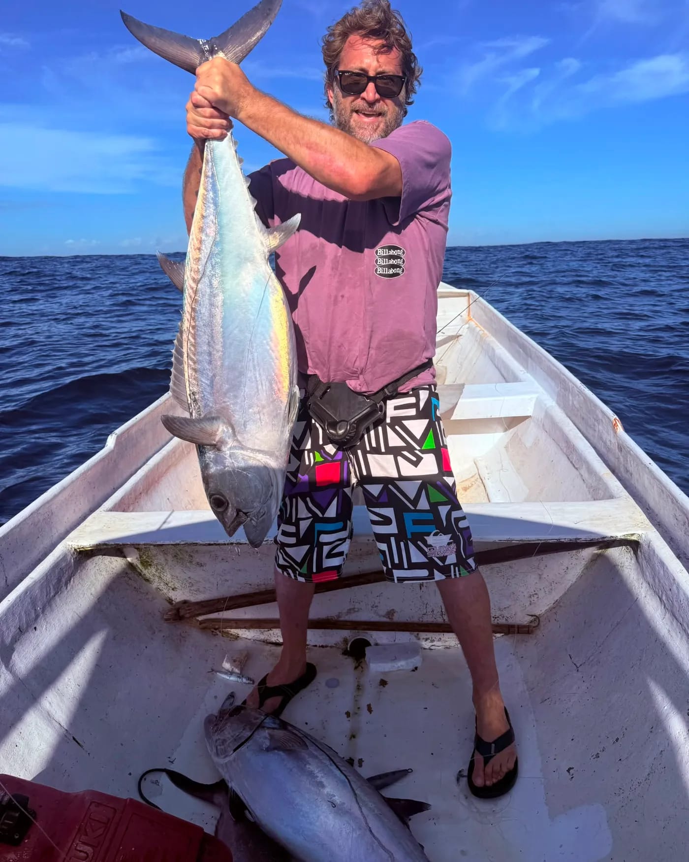 A guest on board holding up a big tuna caught offshore
