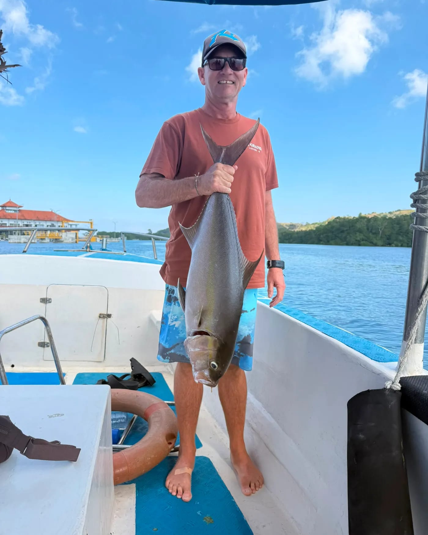 A guest on the boat with a trevally caught on a charter
