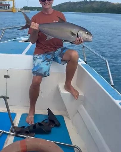 A guest on the boat holding up a fish just landed