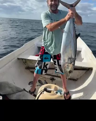 A crew member lifting a tuna caught on the trip