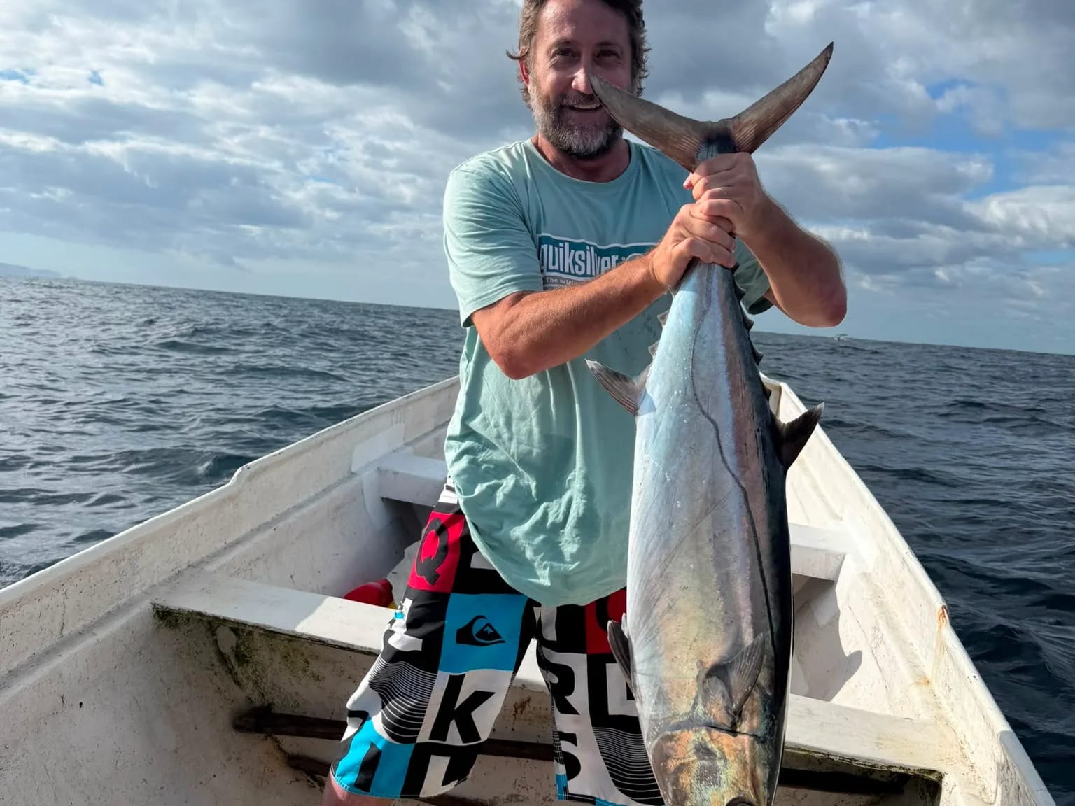 A guest on the boat with a tuna landed offshore
