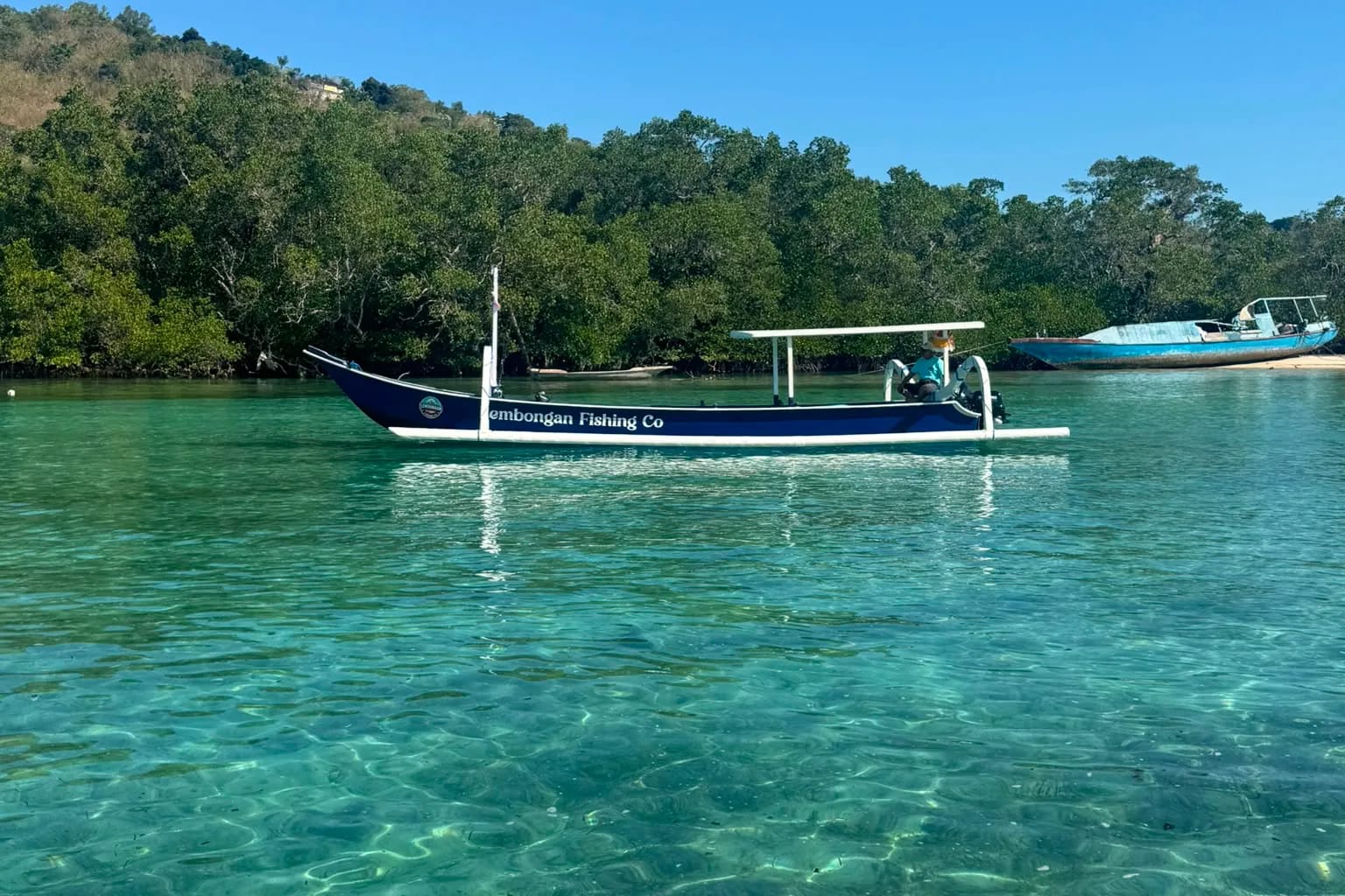 The traditional Lembongan Fishing Co jukung with outriggers moored in clear water